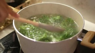 Taze brokoli sobanın üstünde, ahşap bir kaşıkla taze brokoli, sağlıklı pişirme hazırlığı sergiliyor..