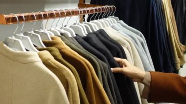 Kadın dükkanda kıyafet seçiyor.