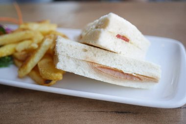 Beyaz dikdörtgen tabakta kızarmış patatesli lezzetli bir sandviç, lezzetli bir yemek hazırlıyor..