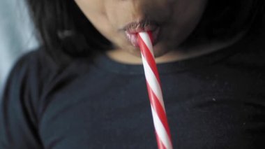 Küçük kız plastik kamışla meşrubat içiyor. .