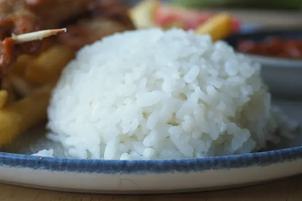 stock image White rice and French fries on a plate with a fork, in a food setting, ready to be enjoyed for a meal