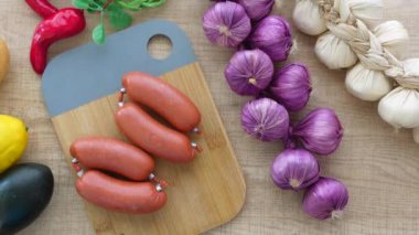 Kesme tahtasında taze sebzelerle çevrili sulu sosisler. Yemek hazırlamak için mükemmel..