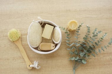 Tahta bir yüzey üzerinde sabun, vücut fırçası, lif ve okaliptüs içeren doğal spa seti..