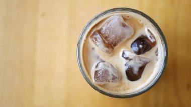 Tahta yüzeyinde buz küpleri olan buzlu bir bardak kahve, sıcak gün içeceği için ideal.