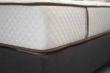 Örgü desenli ve nötr tonlu beyaz bir yatak yakın çekim görüntüsünde rahat bir deneyim sunar.