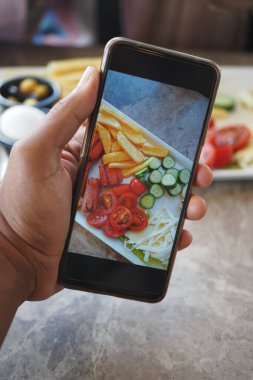 Bu resim akıllı telefon ekranından görülebilen taze sebze ve atıştırmalıkların yakın çekimini gösteriyor.
