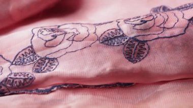 Hassas gül işlemeli yumuşak pembe kumaş yakın plan, güzelliğini ve sanatını sergiliyor.