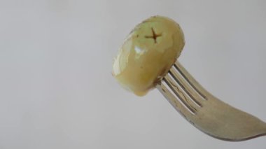 Bir çatalın üzerinde dinlenmiş canlı yeşil bir zeytin, zengin dokusunu sergiliyor.