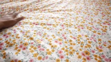 Bir el çiçek desenli kumaş yüzeyine nazikçe dokunur ve zarif dokusunu gösterir.