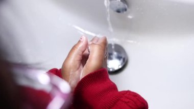  Çocuk, ellerinde sabun ve suyla arındırıcı bir jest yapıyor..