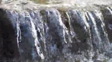 Huzurlu ve huzurlu bir şelale doğal bir ortamda pürüzsüz taşların üzerinde yavaşça akıyor.