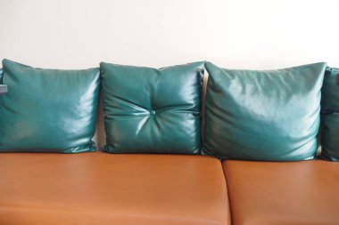 Zarif yeşil yastıklar zarif kahverengi deri bir kanepede güzelce dizilmiştir.