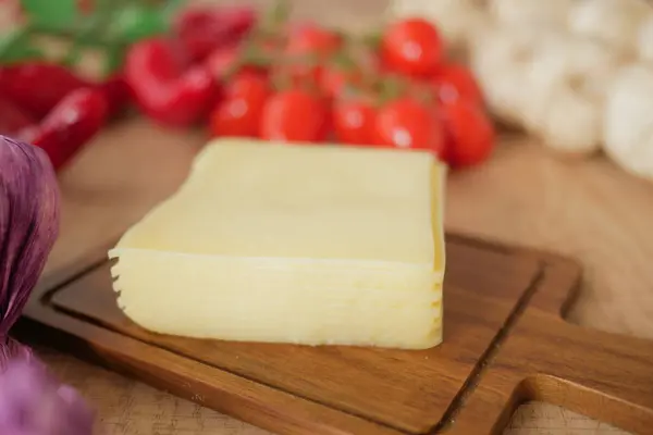 stock image A delicious slice of cheese, perfectly surrounded by a variety of fresh, vibrant vegetables