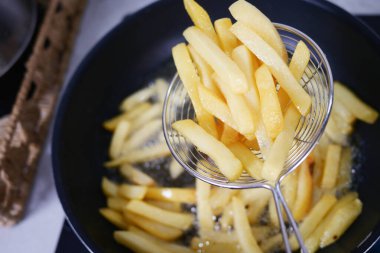 Kızartma tavasından çıtır çıtır patates kızartmaları ustalıkla kaldırılıyor. Tadını çıkarmaya hazır.