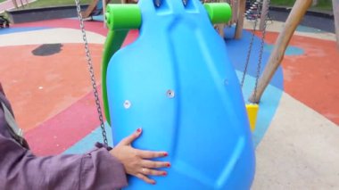  Çocuk parkta salıncakta sallanırken eğleniyor.