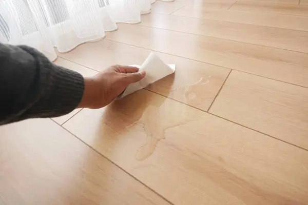 stock image hand wiping spilled tea with paper napkin on floor