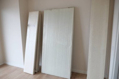 Geniş, boş bir odada düzgünce düzenlenmiş bir yığın açık renkli tahta panel var.