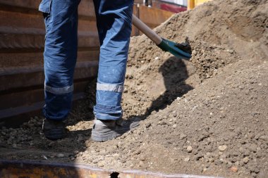 Bir insan topraktan toprak çıkarmak için kürek kullanıyor..