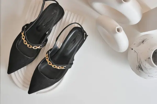 Stock image These stylish black slingback heels come complete with a chic gold chain accent for added flair