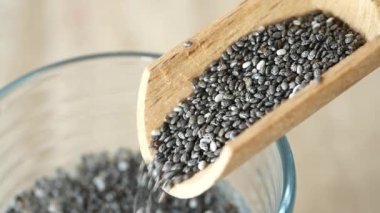 Tahta kaşıktan chia tohumları dökülüyor. ,