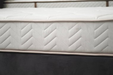 Örgü desenli ve nötr tonlu beyaz bir yatak yakın çekim görüntüsünde rahat bir deneyim sunar.