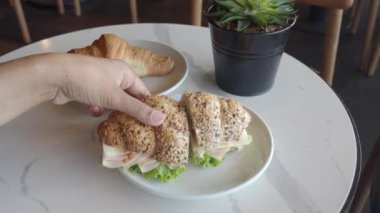 Lezzetli bir sandviç, taze marullu, rahat bir kafede masanın üzerinde zarif bir şekilde servis ediliyor.