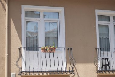 Canlı çiçekler ve zarif beyaz pencerelerle süslenmiş büyüleyici bir balkon cazibesini artırıyor.