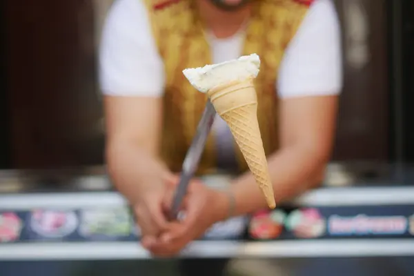 stock image A friendly vendor serves a tasty ice cream cone under the warm sunshine, spreading joy