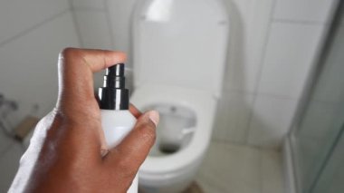 Bir el, temiz ve sterilize edilmiş bir tuvalete yakın bir yerde oda spreyi sıkıyor.