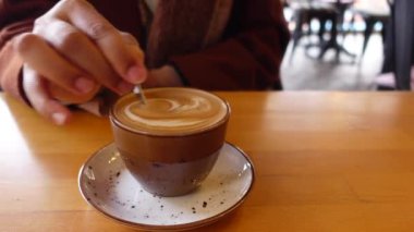 İnsan, kaşıkla kahve karıştırır.