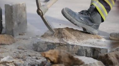 Kendini adamış bir inşaat işçisi gürültülü bir şantiyede beton kıran bir kaya matkabını kullanıyor.
