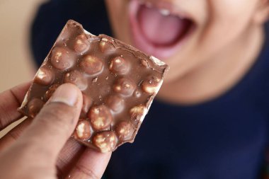 Neşeli ve heyecanlı bir çocuk ellerini lezzetli bir çikolatalı atıştırmalık için uzatıyor.