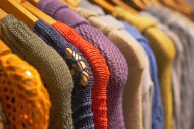 Canlı ve şık bir örgü süveter koleksiyonu ahşap askılarda güzelce sergileniyor.