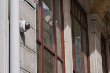 Bir binanın duvarındaki yüksek çözünürlüklü güvenlik kamerası yakınlardaki pencere ışığını çok güzel yansıtıyor.