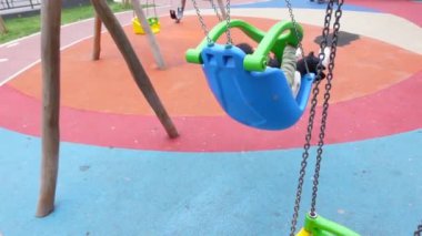  Çocuk parkta salıncakta sallanırken eğleniyor.