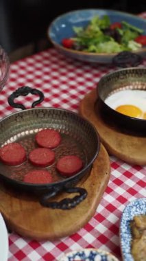 Mükemmel pişmiş yumurta ve kareli masa örtüsünün üstünde kızarmış etle nefis bir kahvaltı sahnesi.