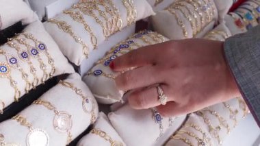 Güzel bir vitrinden zarif ve lüks altın mücevherler seçen bir el.
