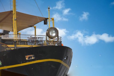 Eski bir gemi bulutlu mavi bir gökyüzü altında zarif bir şekilde yelken açar ve büyüleyici bir manzara yaratır.