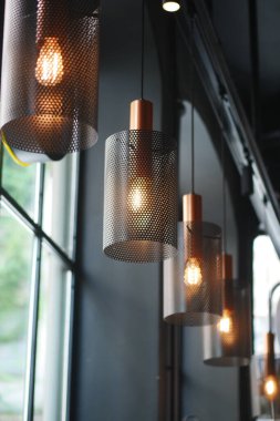 Modern bir kafede asılı parlak kolye ışıkları ve sıcak bir ortam.