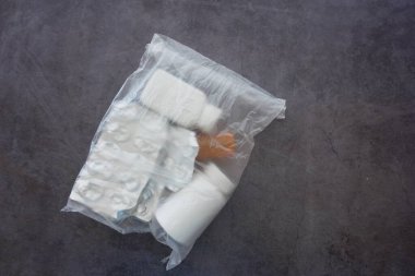 Mühürlü plastik bir torba içinde çeşitli ilaç şişeleri ve su toplayan paketler var.