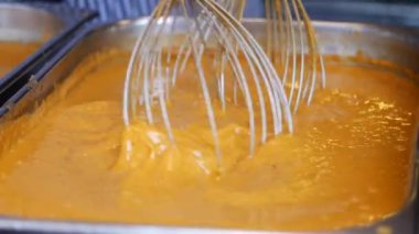 Geniş bir mutfak tepsisinde çırpıcıları kullanarak kremalı kabak püresini karıştır ve karıştır.