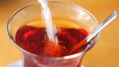 Bu, cam bardakta karıştırılan şekerli demlenmiş çayın yakın plan bir görüntüsü.