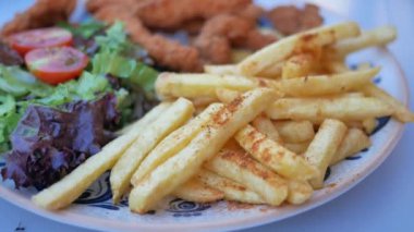 Kızarmış patates, ızgara tavuk ve taze, çıtır çıtır salata ile dolu renkli bir tabak.