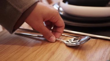 Zarif bir şekilde düzenlenmiş çatal bıçak takımı, ambiyansı geliştirmek için şık, koyu bir masa örtüsü üzerinde sergileniyor.