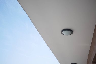 Modern tavan tasarımı açık mavi gökyüzüne karşı şık bir aydınlatma armatürü içerir.