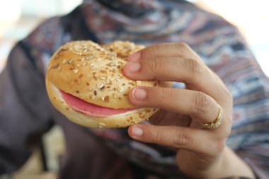 Bir el susamlı çörek. Şarküteri etiyle dolu. Atıştırmalık için mükemmel..