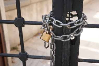 Sağlam ve sağlam bir zincir ve sağlam bir asma kilit metal bir kapıya takılır.