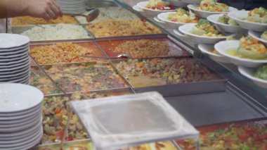 Değişik lezzetli yemekleri olan renkli bir büfe ve herkes için taze, sağlıklı salatalar.