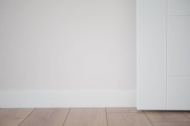 Işık duvarları ve ahşap döşemeleri olan minimalist bir oda, açık ve havadar bir atmosfer yaratıyor.