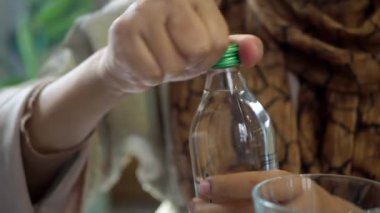 Bir insan ustalıkla üzerinde yeşil bir kapak olan plastik bir su şişesini açıyor.